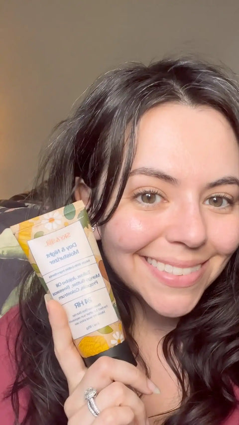 Smiling woman showing the front of The Everything Cream tube