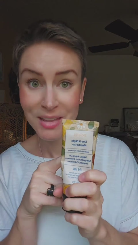 Woman holding a tube of Sky & Sol The Everything Cream and smiling